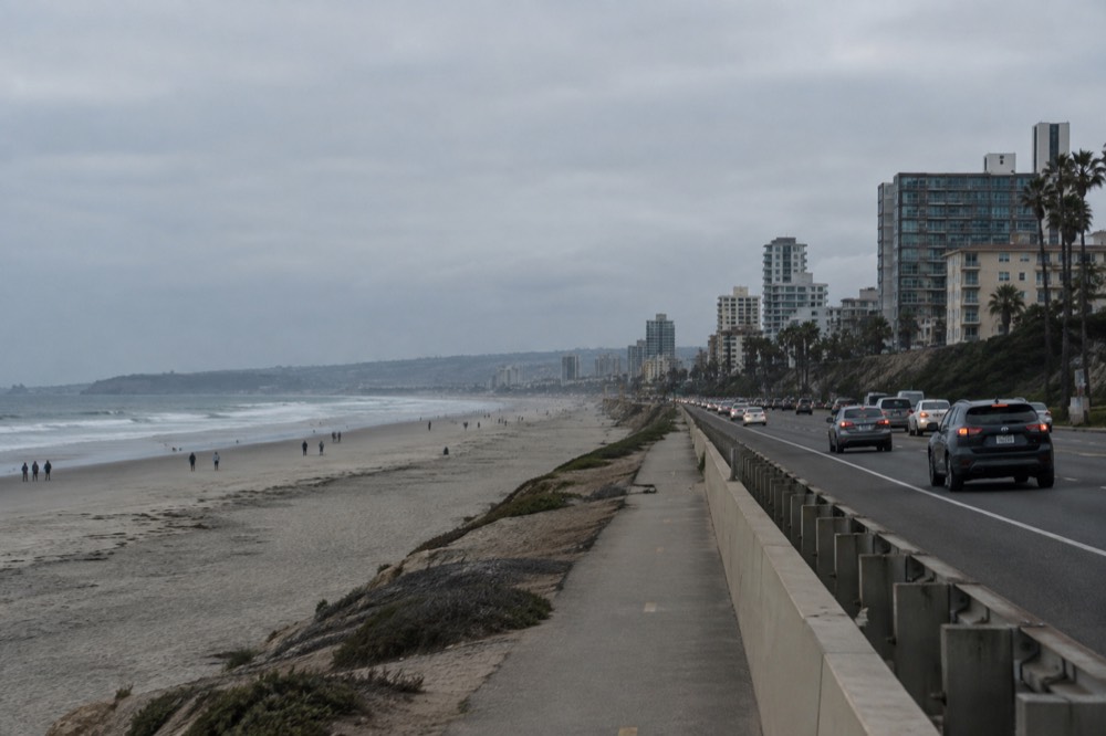 Coastal freeway with traffic lanes beside a wide sandy beach