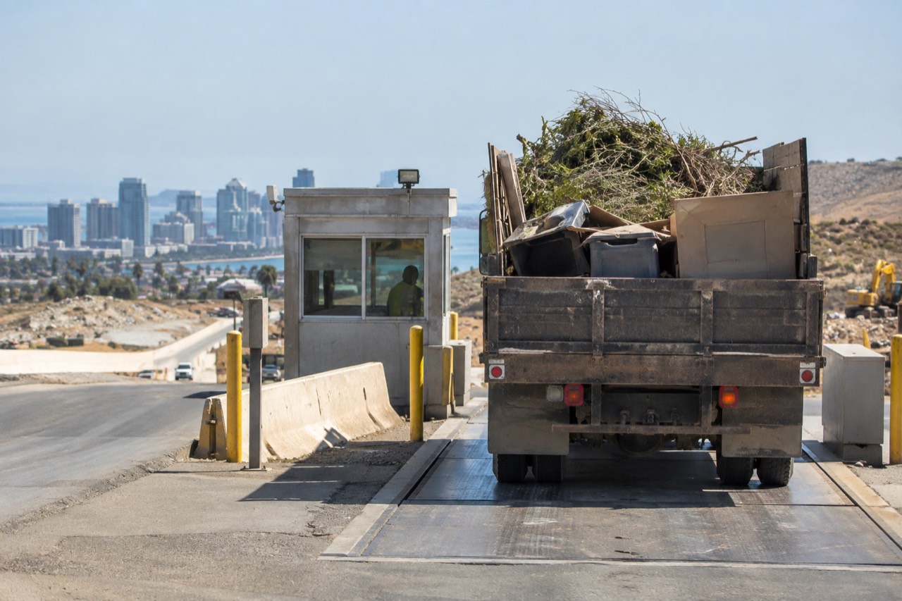 A truck loaded with yard waste and boxed junk waiting at a landfill scale house