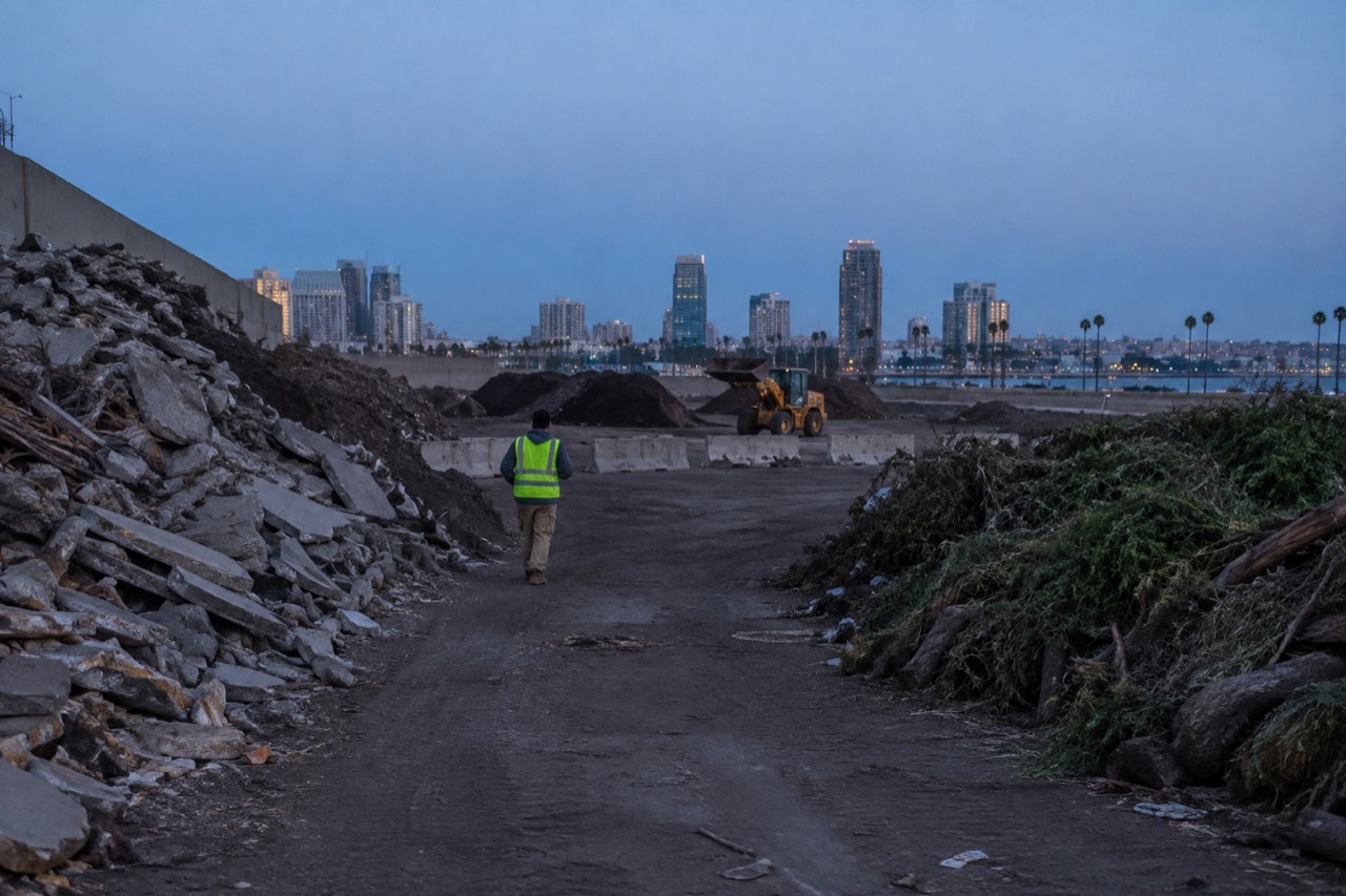 A landfill disposal area with sorted piles of construction debris and green waste under a clear sky