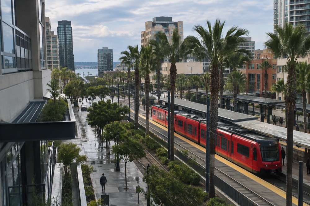 Trolley stopped at a downtown San Diego station with palm trees behind it