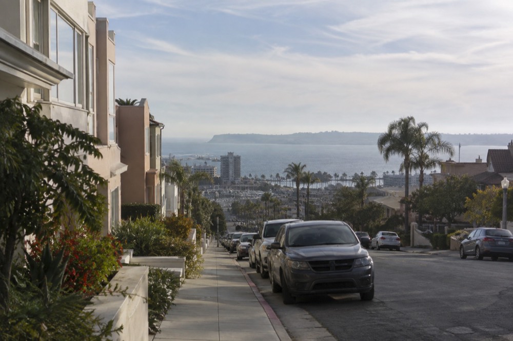 Row of pastel houses on a hillside street overlooking the San Diego coastline