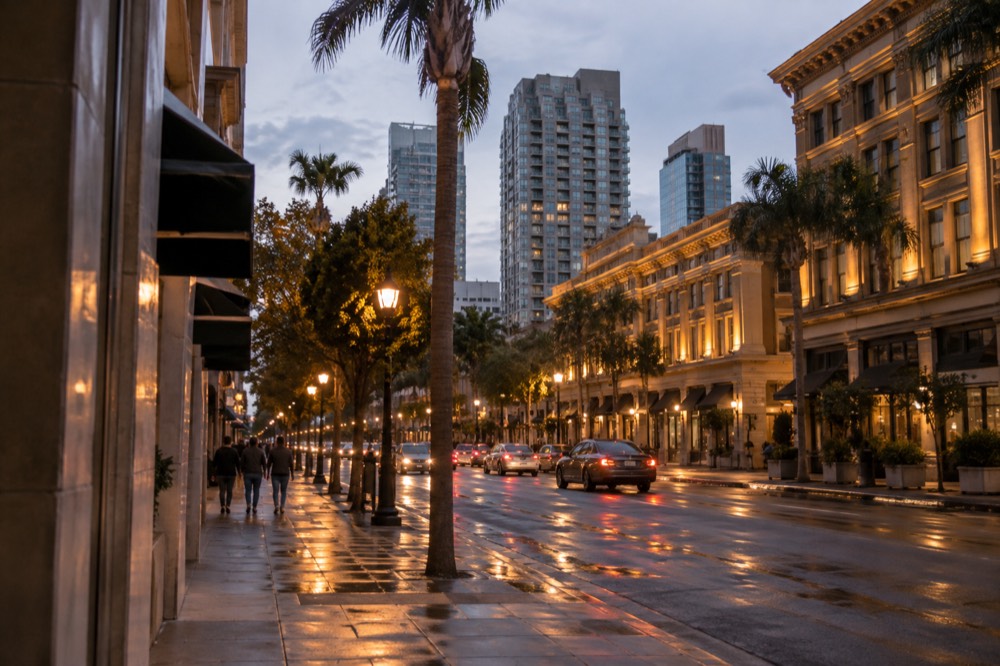 Illuminated historic buildings along a downtown San Diego street at dusk