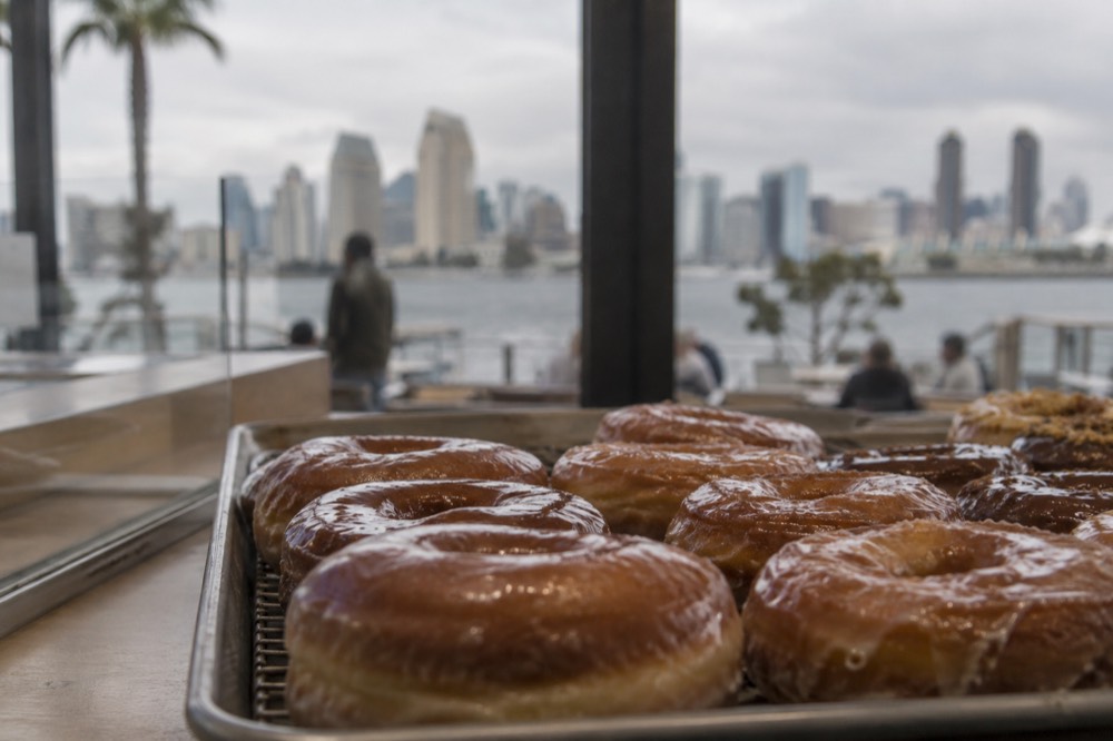 A tray of freshly glazed donuts arranged on a bakery counter