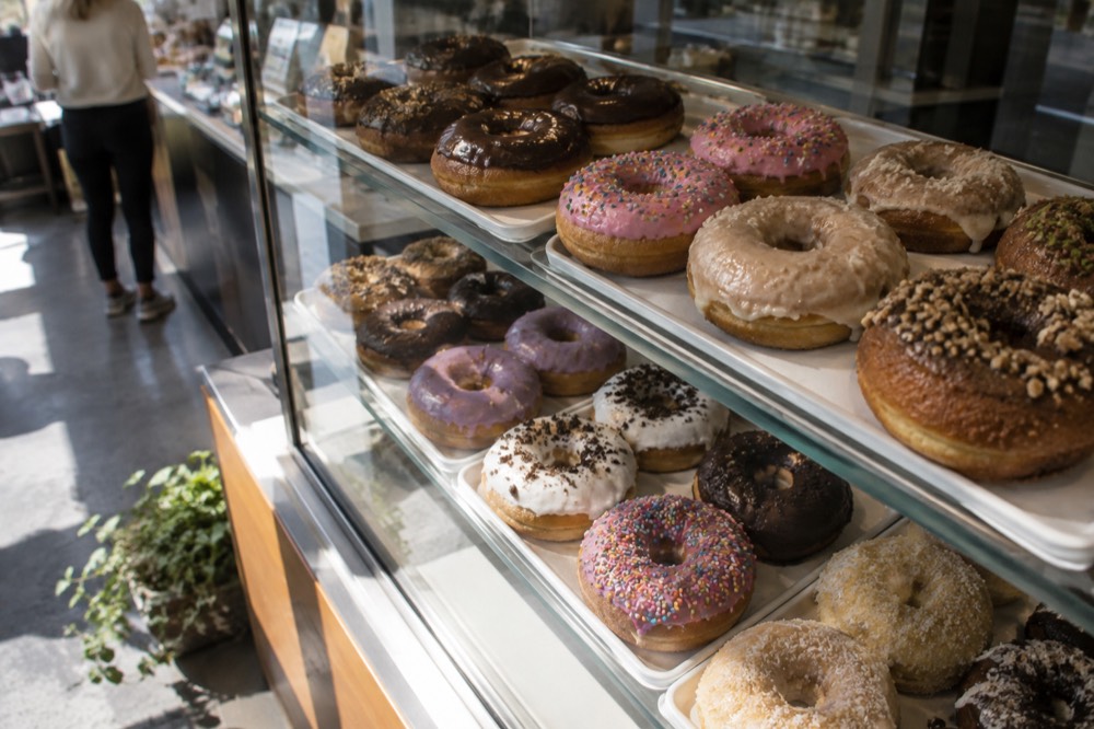 A display case filled with colorful frosted donuts inside a small bakery
