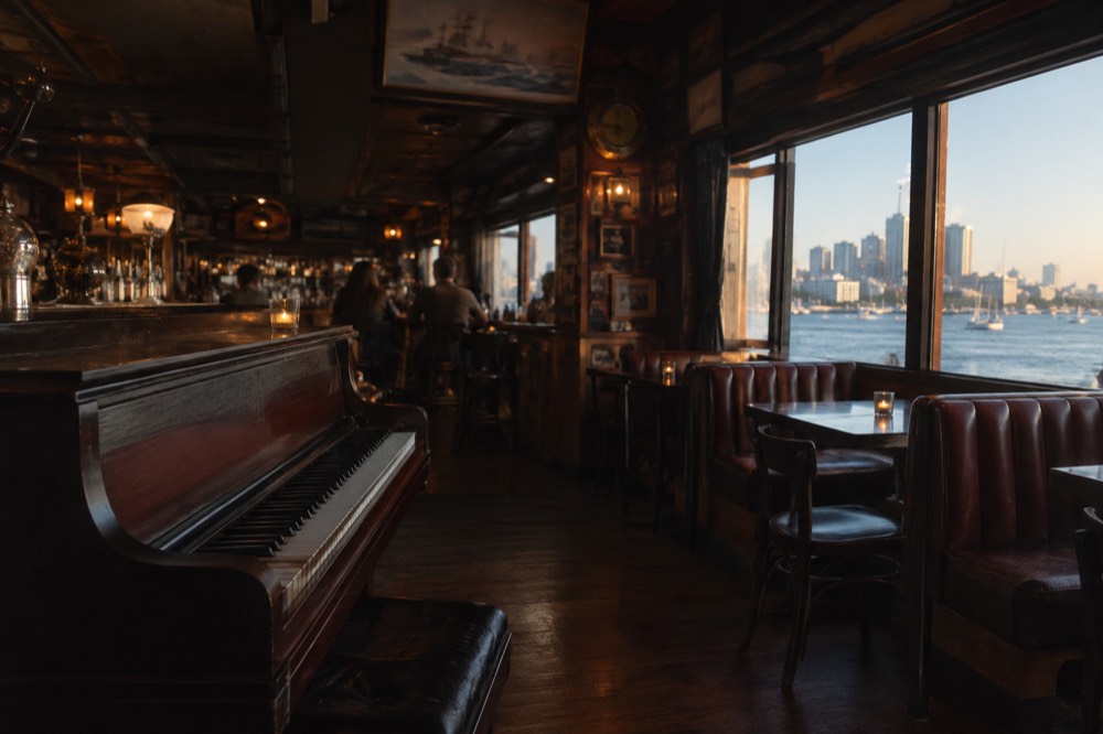 A dimly lit bar interior with a piano, hanging memorabilia and wooden booths