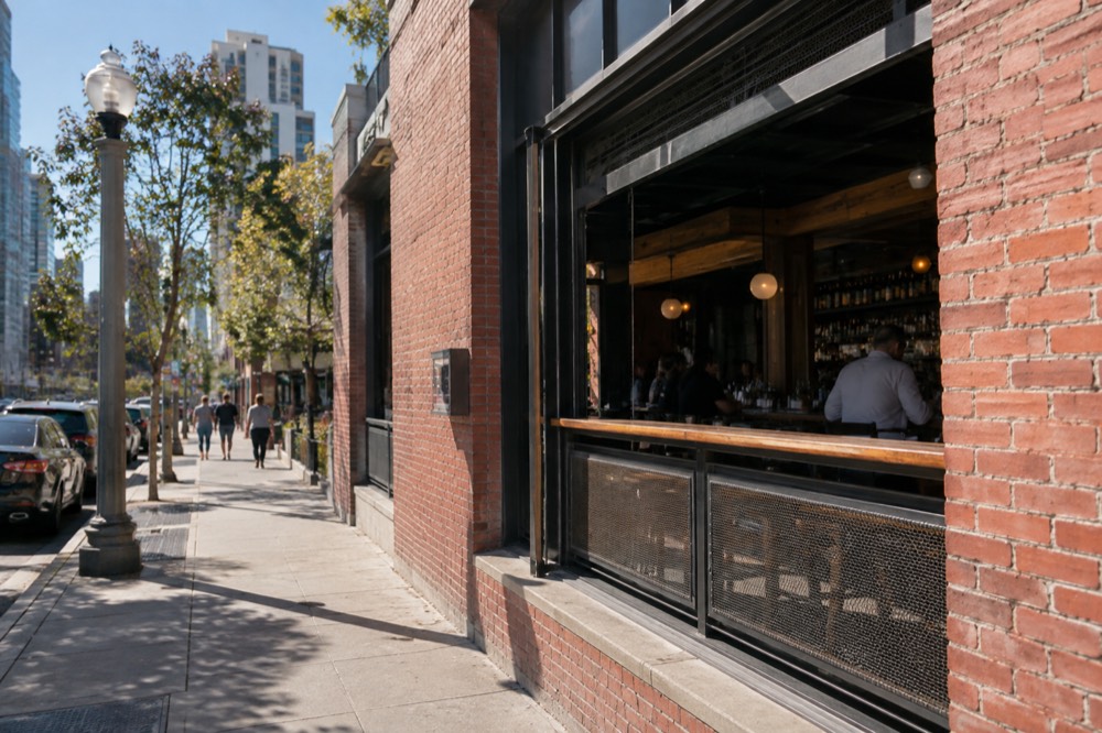 A brick bar building exterior on a downtown street with a small sign above the door