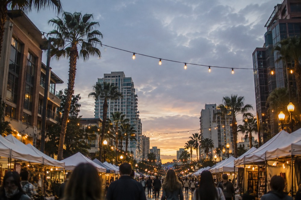 Crowded festival booths and string lights along a downtown street at dusk