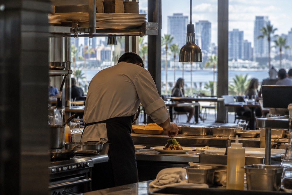 A chef plating a dish in an open restaurant kitchen