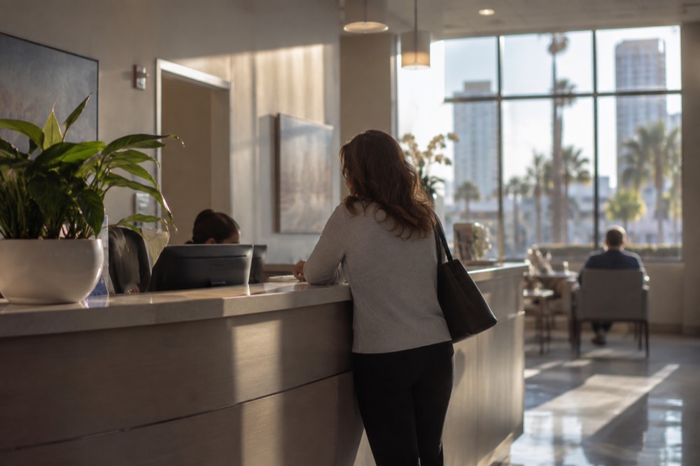 A clinic reception desk with a sign-in kiosk in a bright waiting room