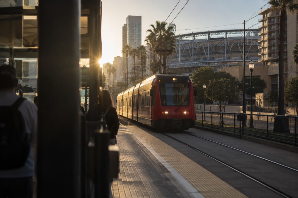 A city trolley arriving at a downtown station with a stadium visible in the background