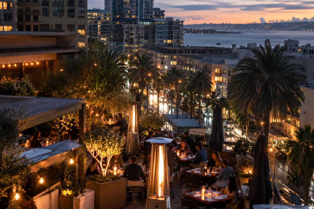 A restaurant patio in a downtown San Diego neighborhood lit up in the evening