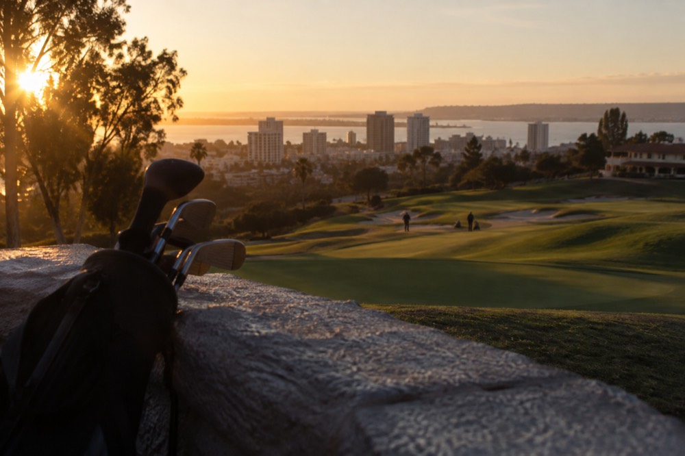 Rolling fairway bunkers and a distant clubhouse roofline at dusk