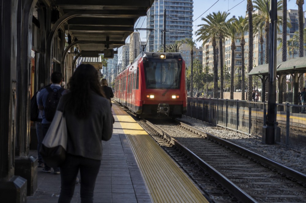A trolley station platform near downtown San Diego with a train arriving