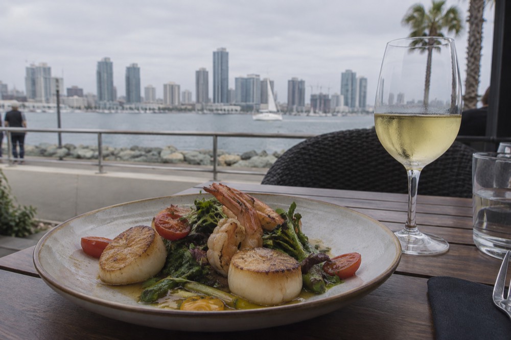 Plated seafood dish on a restaurant table with a glass of white wine