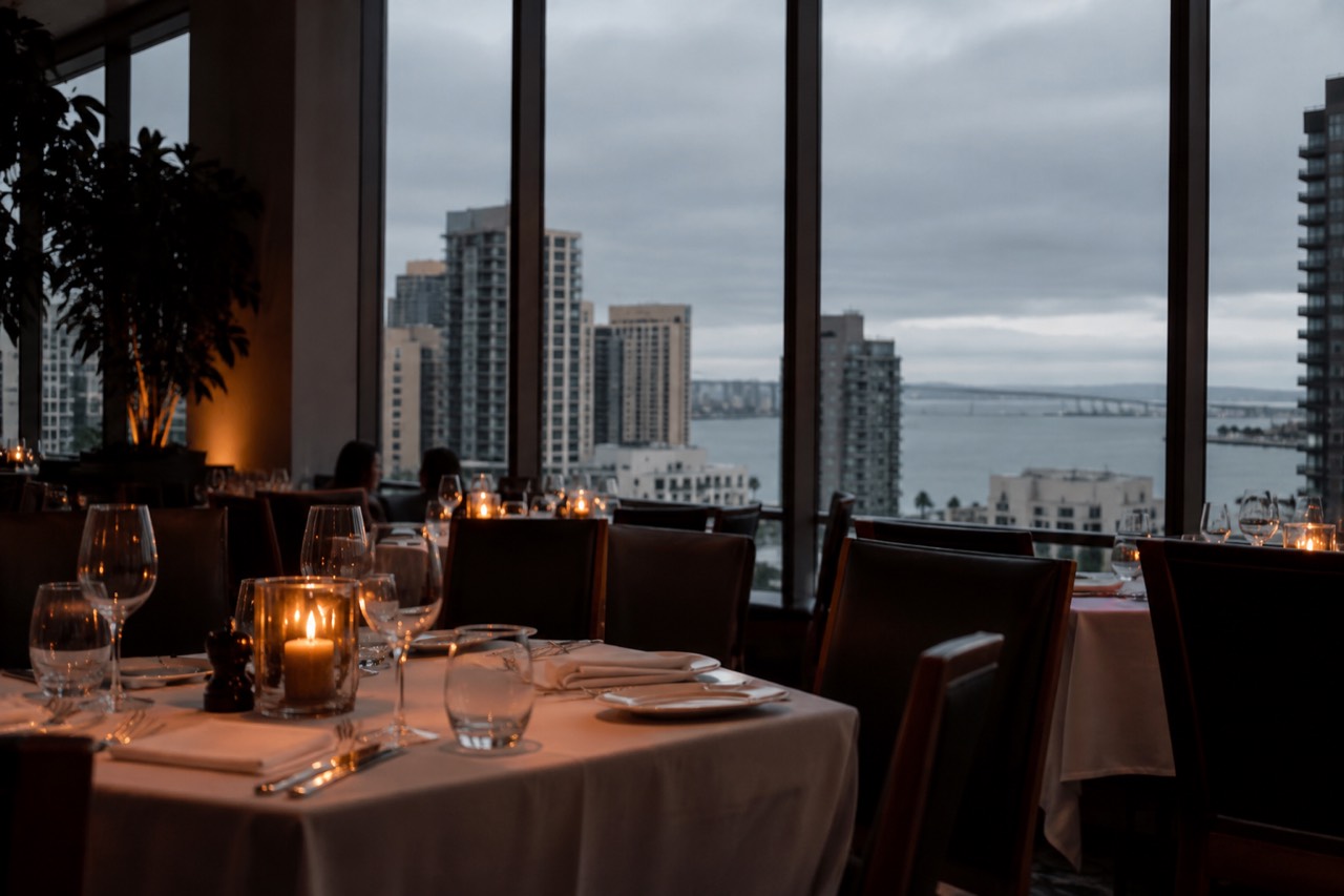 An elegant candlelit dining room with white tablecloths and wine glasses set for evening service