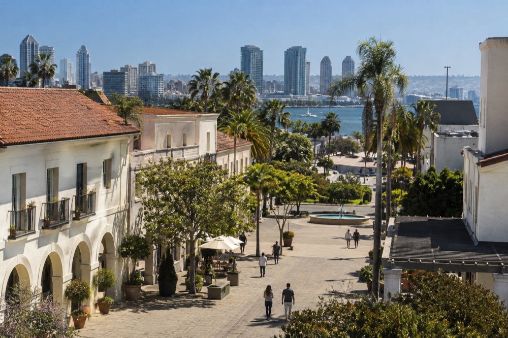Historic downtown street with adobe buildings and a plaza under a clear sky