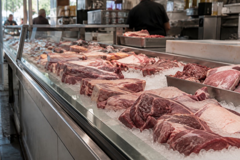 A butcher counter with cuts of meat displayed on ice in a San Diego market