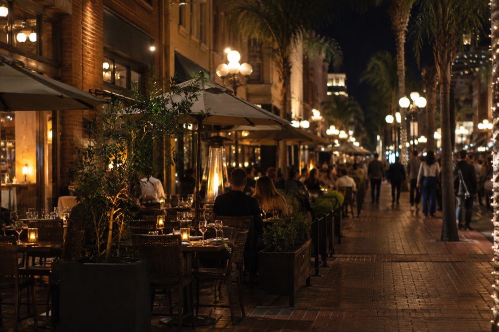 Outdoor restaurant tables along a lit pedestrian street in the Gaslamp Quarter at night