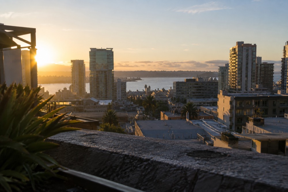 View over San Diego rooftops toward the bay with hills in the distance