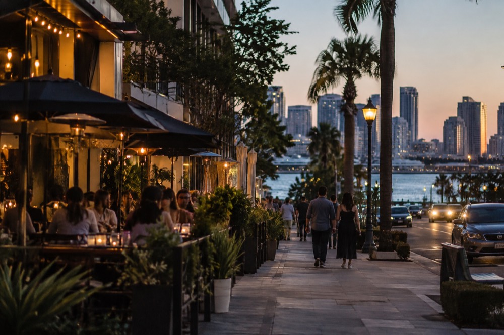 An evening street scene with lit restaurant patios along a city block