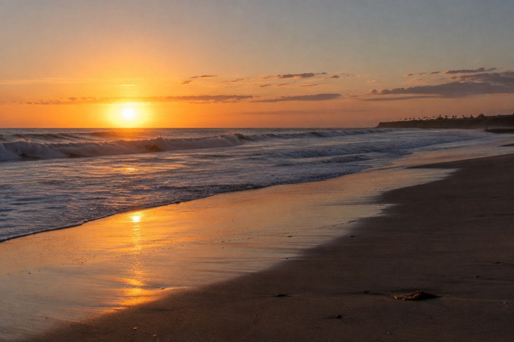 Ocean beach at sunset with waves breaking and an empty stretch of sand
