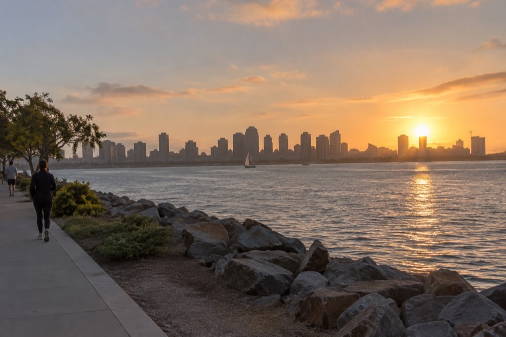 Downtown San Diego skyline seen across the bay from a Chula Vista waterfront path at sunset