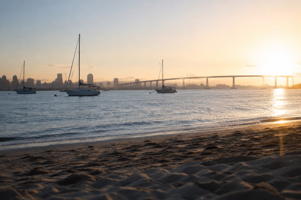 Sailboats on calm bay water with Coronado and the bridge in the background