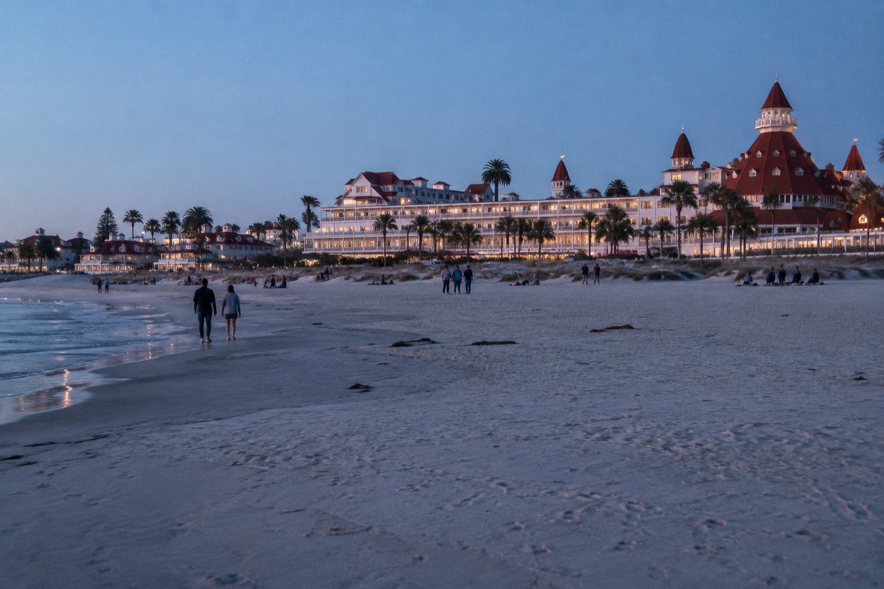 Wide view of Coronado Beach with the Hotel del Coronado red turrets in the background under a clear sky