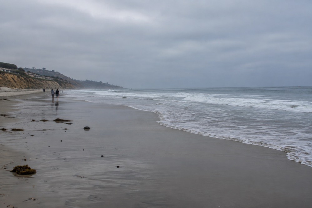 Gentle waves rolling onto smooth wet sand at Del Mar beach in soft light