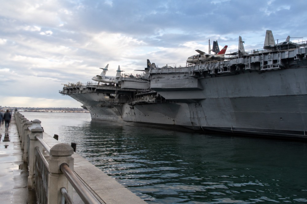 Flight deck of an aircraft carrier with restored jet aircraft lined up along the bow