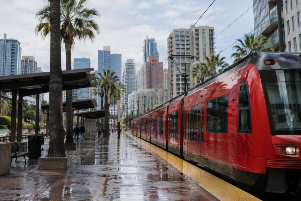 Red trolley car at a downtown station with the skyline behind it