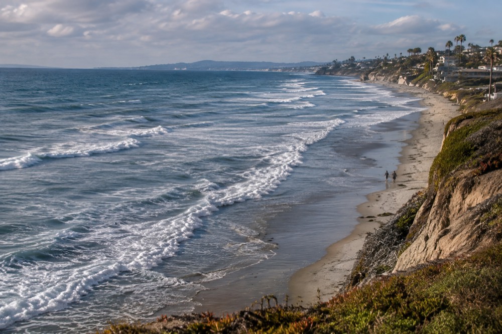 Encinitas coastline with waves breaking over a sandy beach and bluffs in the background