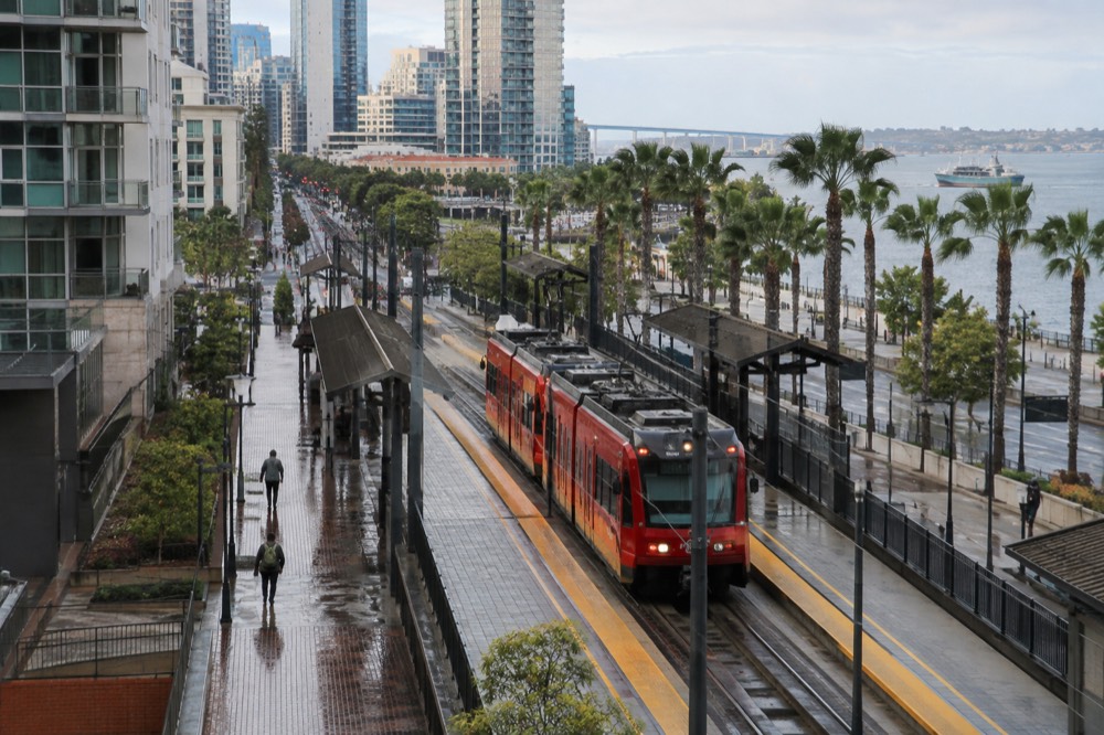 Red trolley arriving at a downtown San Diego street station near the waterfront