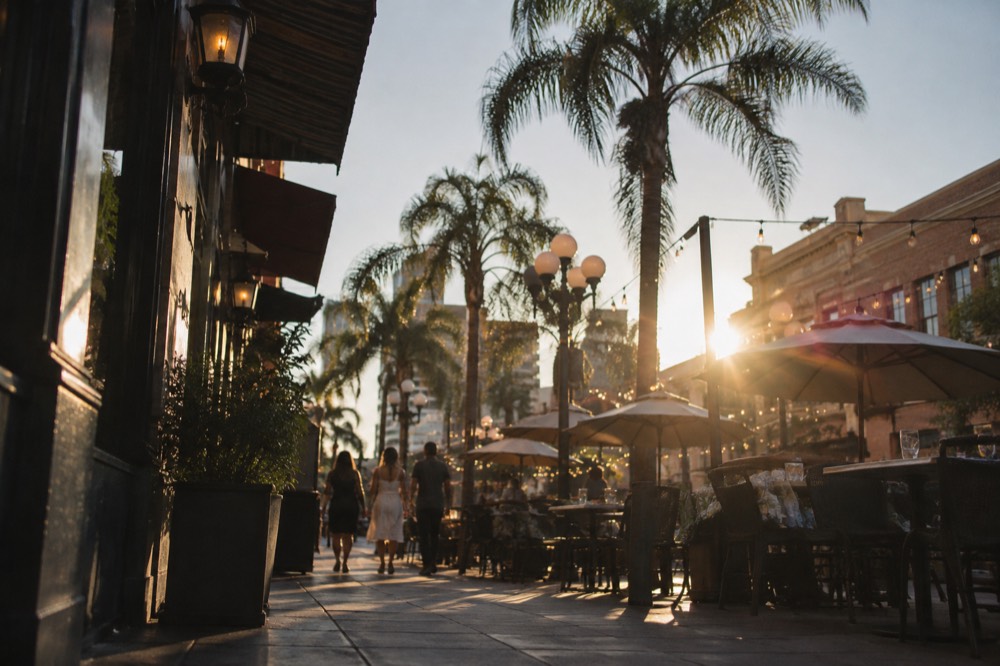 Sidewalk tables and string lights outside restaurants on a Gaslamp Quarter street in the evening