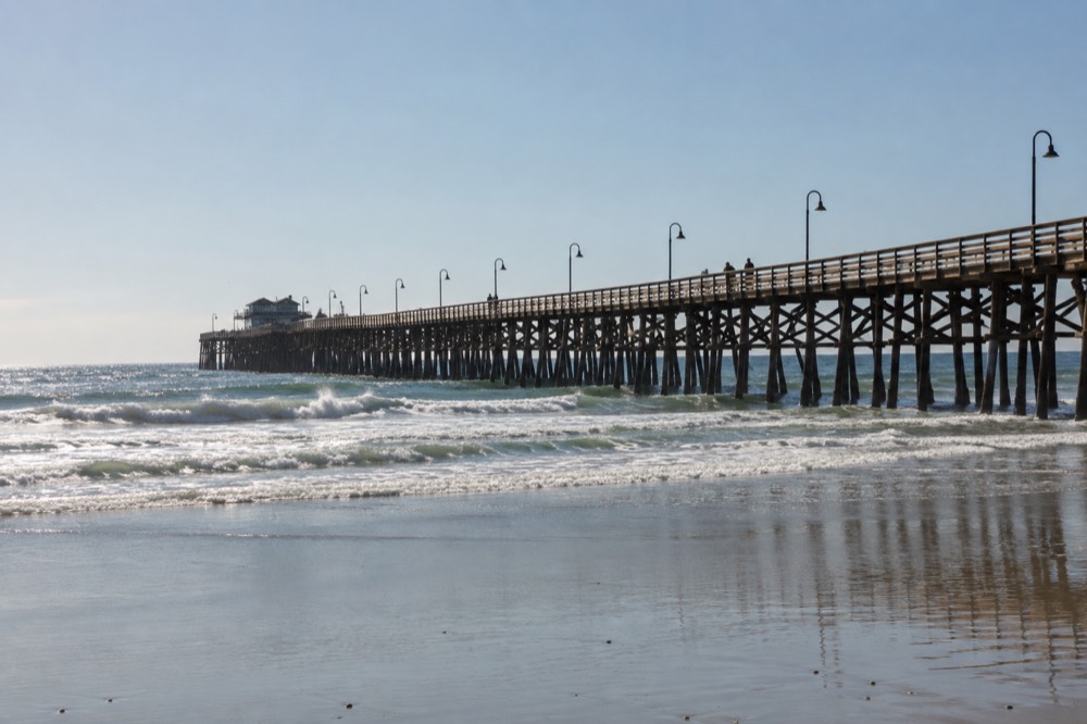 A long wooden pier extending over gentle ocean waves toward the horizon