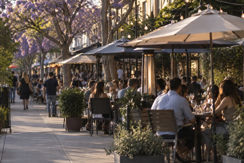 Bustling evening street with people dining at outdoor tables under market lights