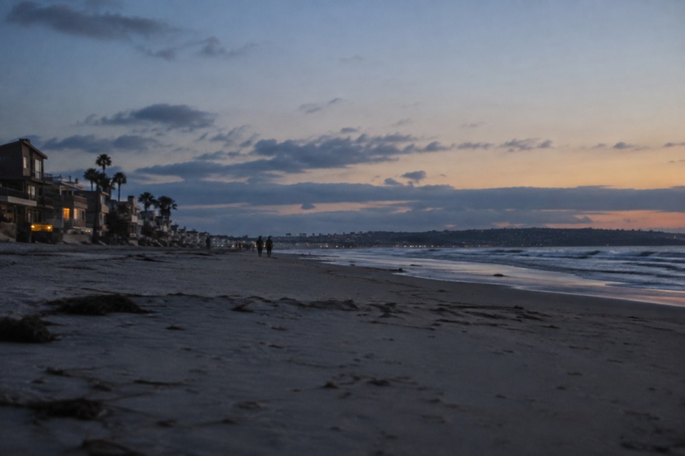 An empty beach in the late afternoon with long shadows across smooth sand