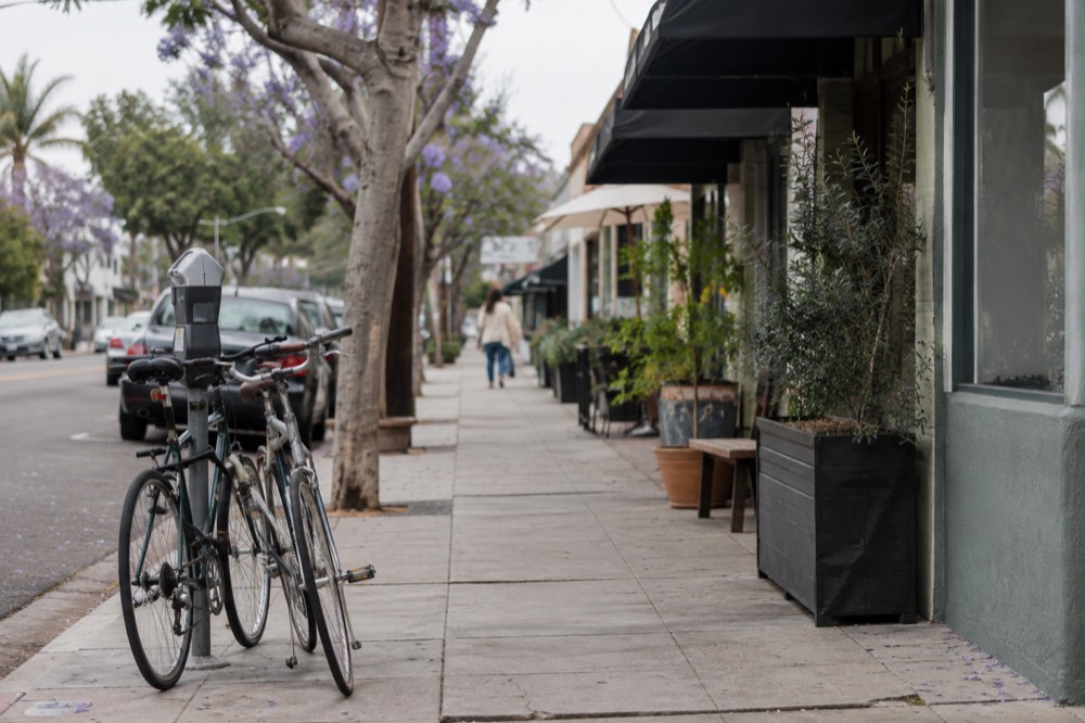 Row of storefronts with awnings and bicycles locked to a meter on a residential corner