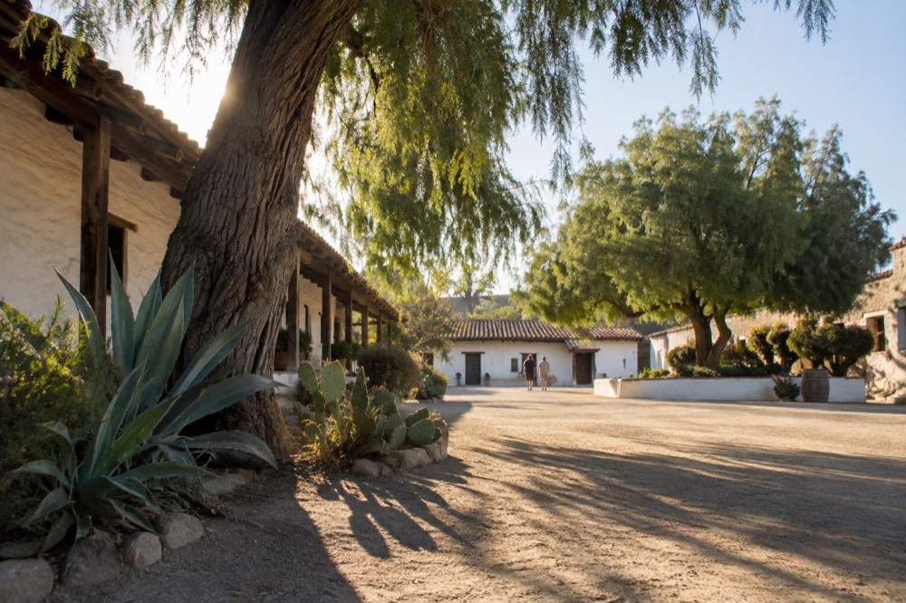 Sunlit historic plaza with adobe buildings and shade trees in Old Town San Diego