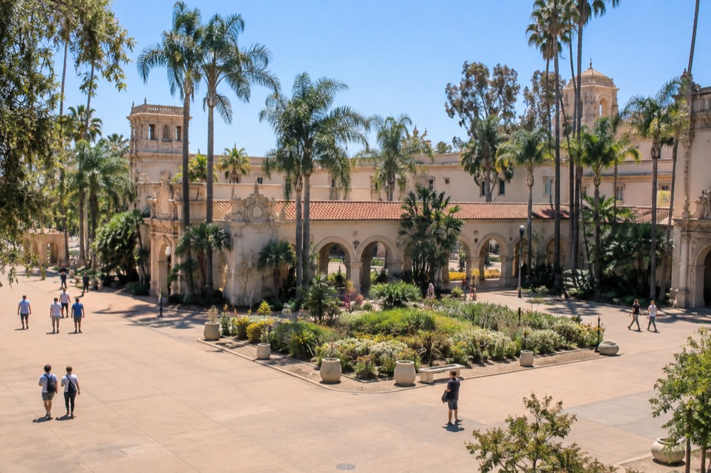 Wide plaza with ornate arches, towers and palm trees in a large park