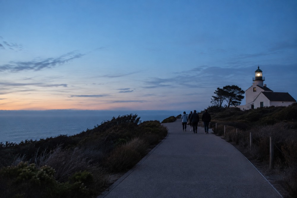 Visitors walking the paved path between the visitor center and the Old Point Loma Lighthouse