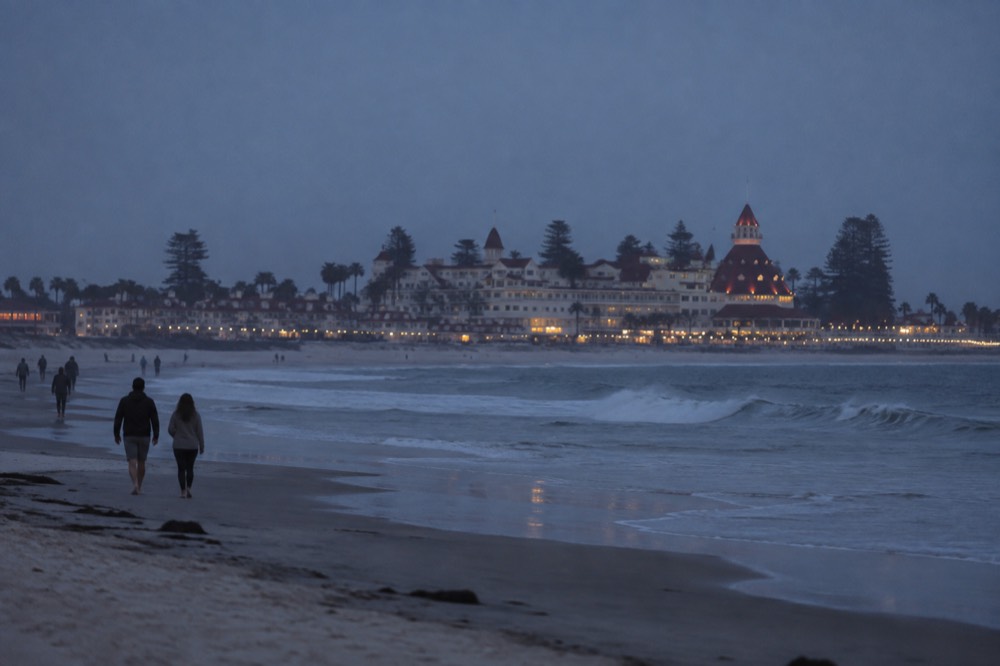 Wide sandy beach with gentle waves and the Hotel del Coronado in the distance under a clear sky