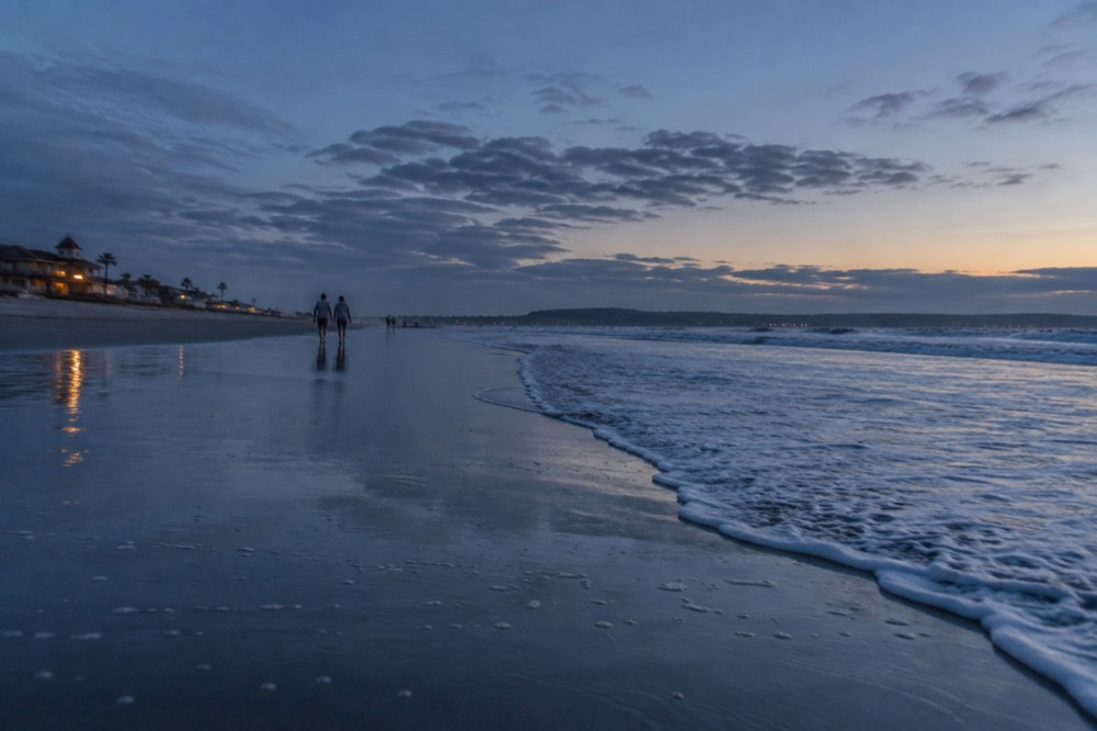 Gentle waves breaking on a wide flat beach with sparkling sand in morning light