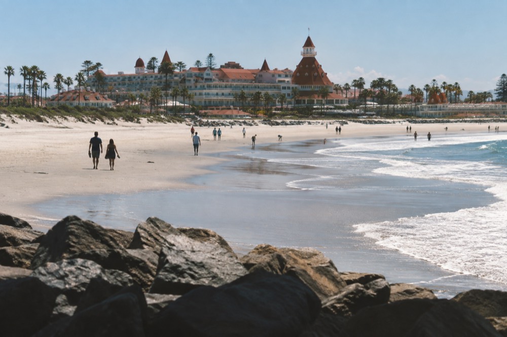 Wide sandy beach with gentle waves in front of a large wooden resort building