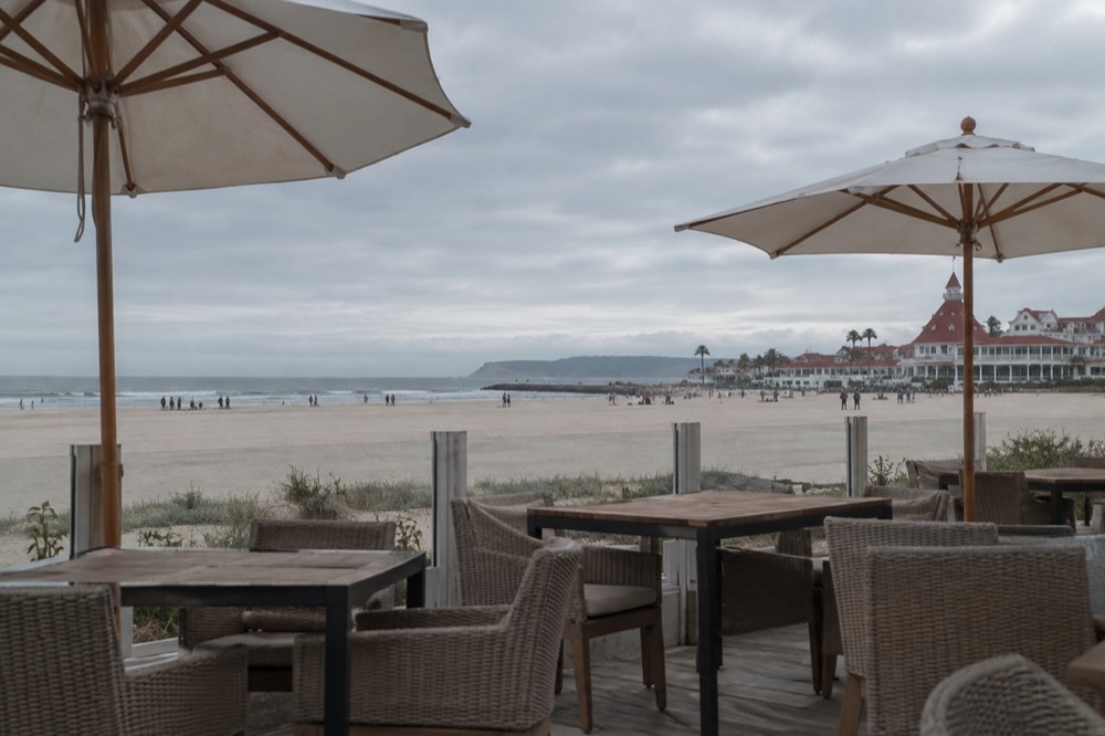 Outdoor terrace tables with umbrellas overlooking a beach and ocean