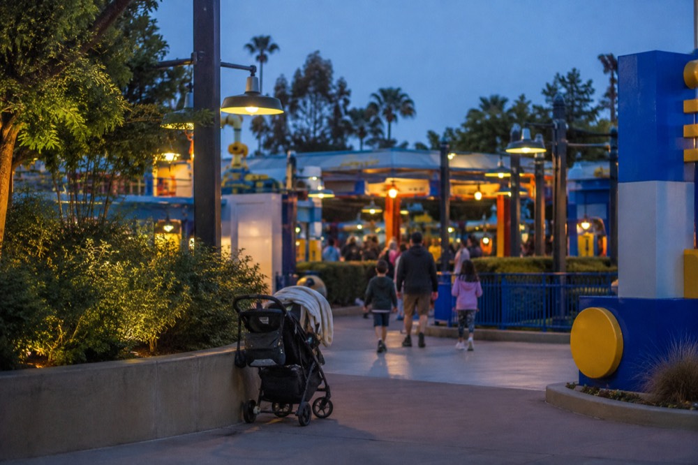 Family stroller parked beside a themed ride entrance with bright brick-style signage