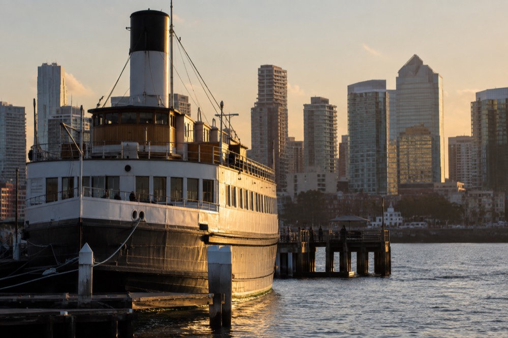 Historic ferry hull moored at the dock with downtown buildings behind