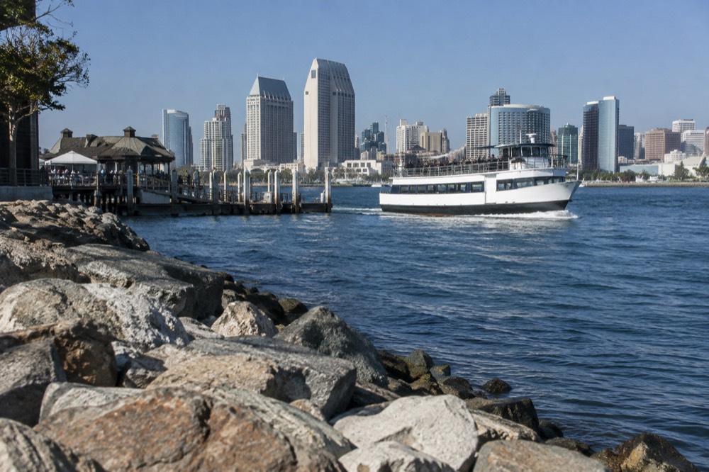 Tour boat leaving a dock on the bay with downtown buildings behind