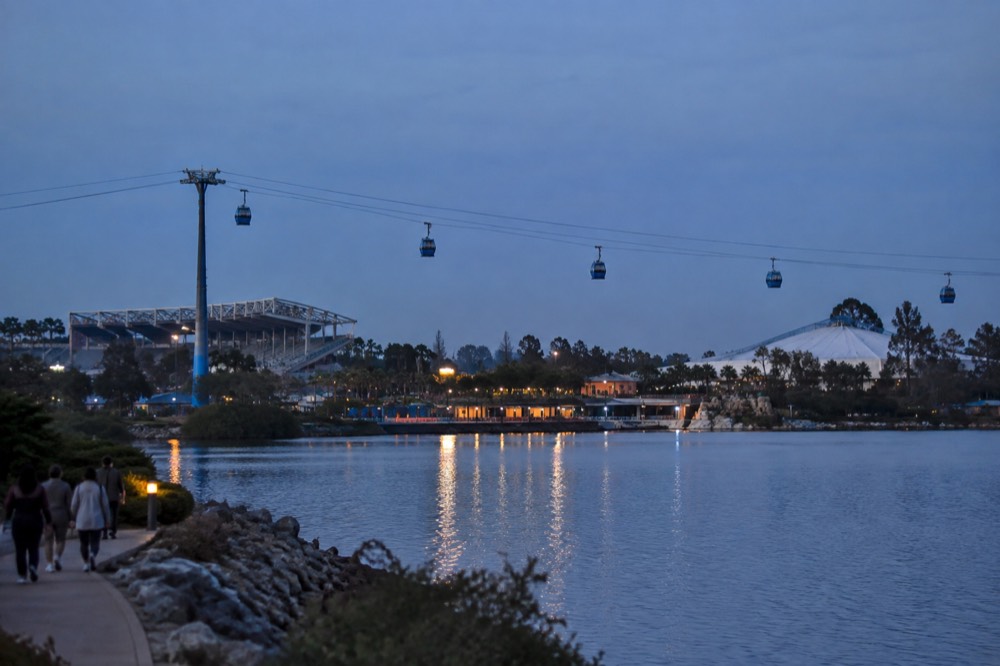 View over a marine theme park with a Skyride gondola crossing a bay and stadium roofs in the distance