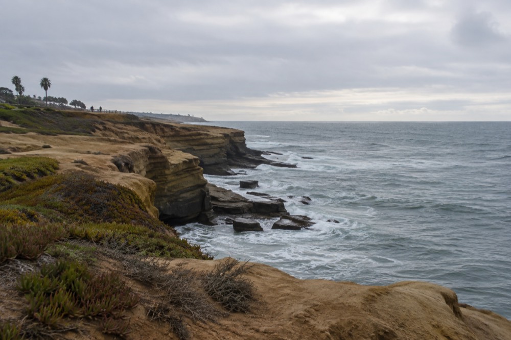 Ocean bluffs at Sunset Cliffs with waves breaking below and open sky toward the horizon